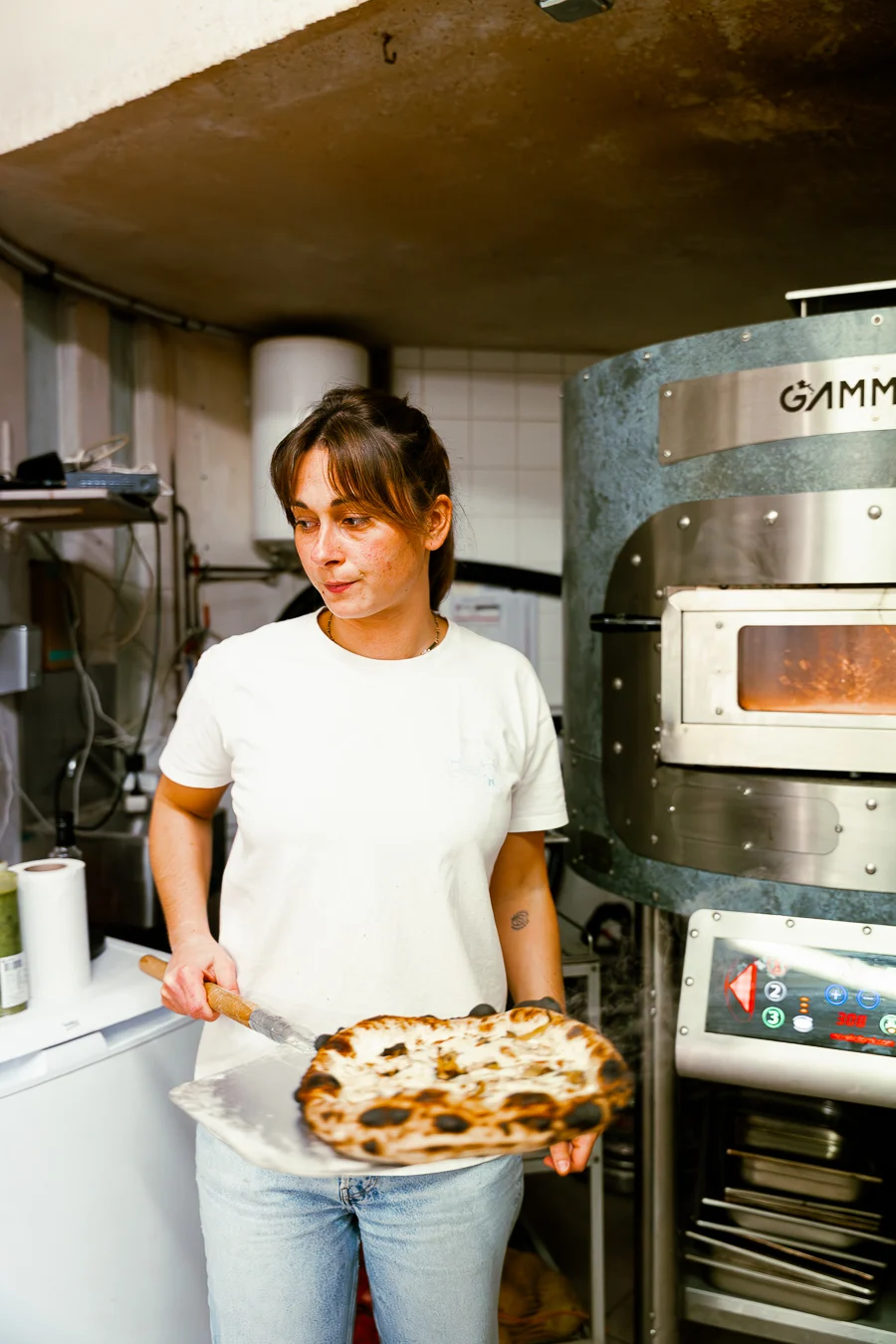 femme sort une pizza d'un four à pizza électrique dans les cuisines d'une restaurant italien reportage photographe culinaire nantes ciao tutti nantes