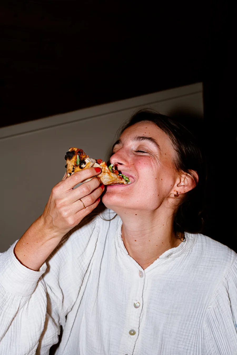 femme mange une part de pizza avec une ambiance flash shooting culinaire