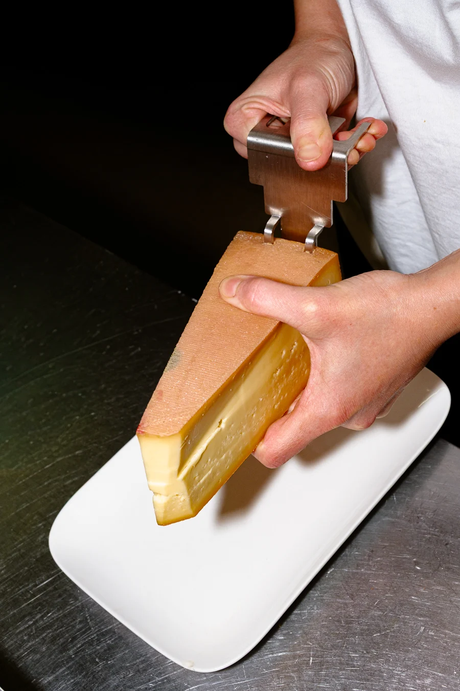 un gros morceau de fromage à raclette dans une assiette pour un shooting culinaire