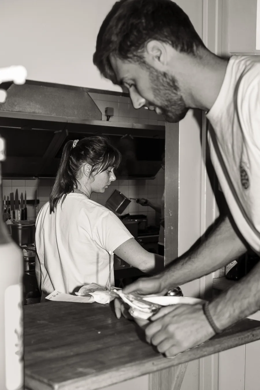 un serveur prend une assiette avec une femme en cuisine photo en noir et blanc shooting culinaire
