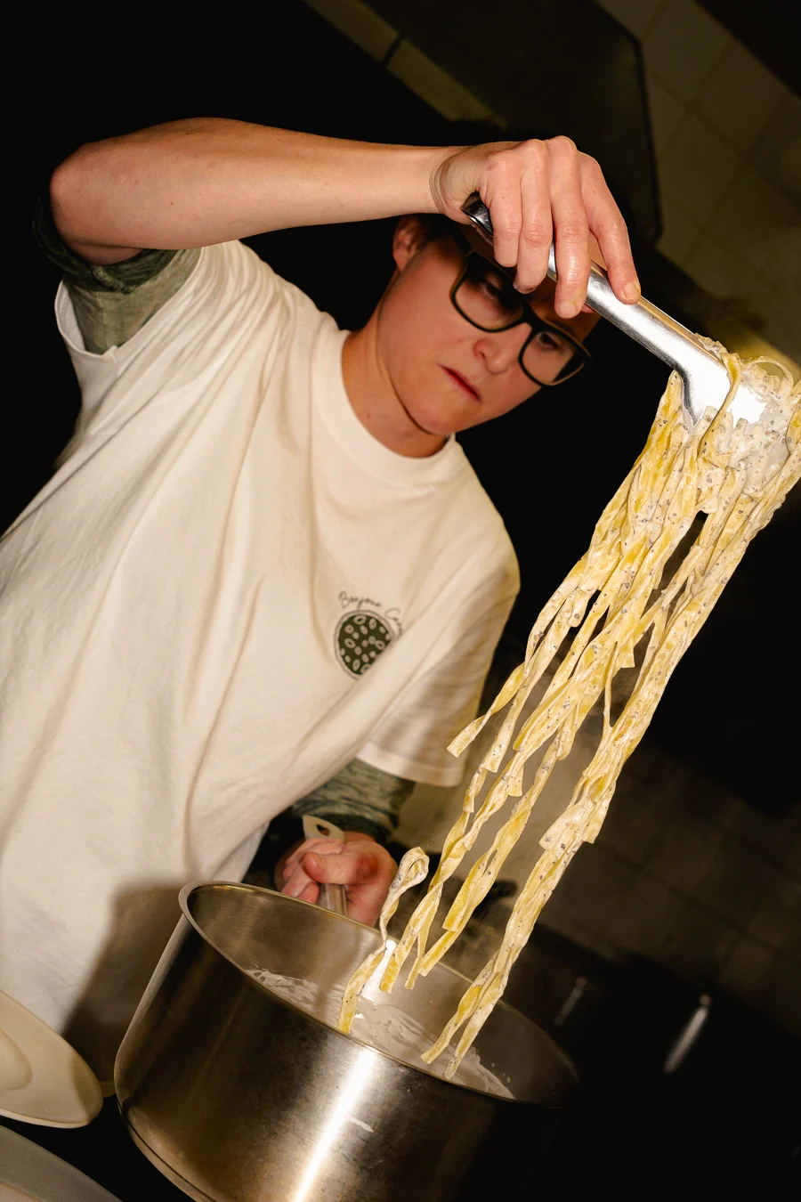 cuisinière qui sert des pâtes fraiches dans une assiettes dans un restaurant italien