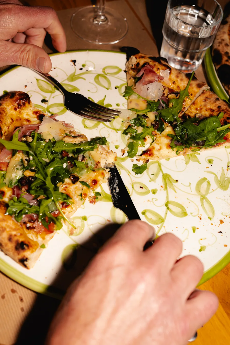 un homme mange une pizza avec de la sauce tomate rouge et de la salade sur une table en bois dans un restaurant italien pour un shooting culinaire ciao tutti studio