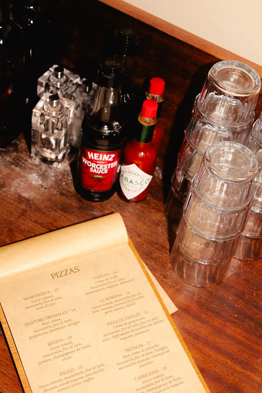table avec des verres, du tabasco rouge du seul et du poivre et la carte du restaurant italien chalet des dunes
