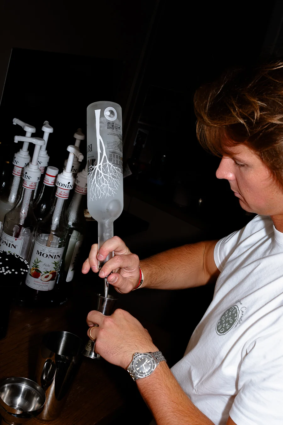 serveur prépare un cocktail avec de l'alcool dans une grande bouteille chalet des dunes restaurant italien